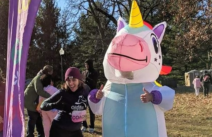 Coach Erin gives two thumbs up with person in blow-up unicorn suit